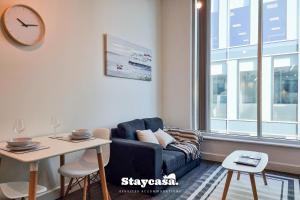a living room with a couch and a table and a clock at Bright & Central Apt - With Great Transport Links in Stockport