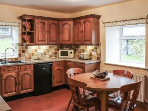 a kitchen with wooden cabinets and a wooden table with a tableablish at Plas Madog in Llanuwchllyn