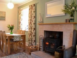 a living room with a fireplace and a table at Clachries Cottage in Boreland of Colvend