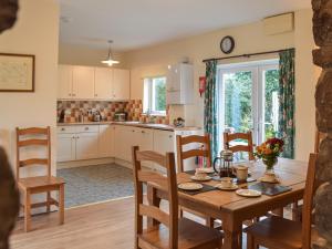 cocina y comedor con mesa de madera y sillas en Cowslip Cottage, en Roch