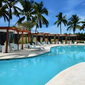 璜多里奧的住宿－Majestuosa villa en Juan Dolio, Guavaberry Golf & Country Club，一个带躺椅的游泳池,棕榈树