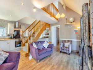 a living room with two purple chairs and a staircase at Ty Teiliwr - Uk45719 in Brynteg