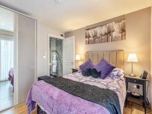 a bedroom with a large bed with purple pillows at Ty Teiliwr - Uk45719 in Brynteg