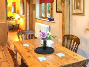 a wooden table with a vase of flowers on it at Bayfield Plus in Foulsham