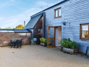 a blue house with a patio and a table at Fig Tree Barn in Worth