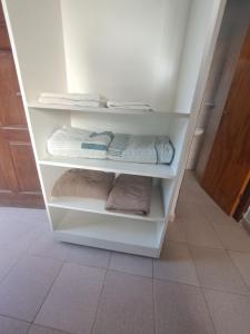 a closet with white shelves with towels and towels at Depto monoambiente temporario in Resistencia