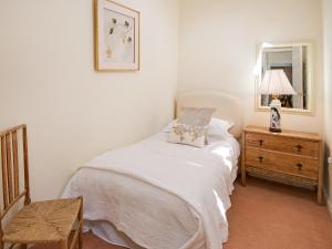 a bedroom with a bed and a dresser with a lamp at Little Swinton - Garden Cottage in Swinton
