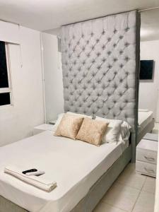 a white bed with a large padded headboard in a bedroom at Increible apartamento en vup in Valledupar