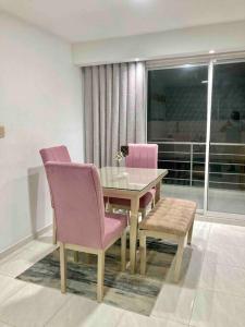 a dining room with a glass table and pink chairs at Increible apartamento en vup in Valledupar