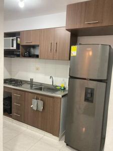 a kitchen with a stainless steel refrigerator and wooden cabinets at Increible apartamento en vup in Valledupar