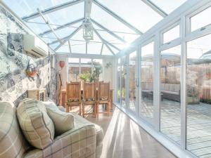 ein Wohnzimmer mit einem Wintergarten aus Glas und einem Sofa in der Unterkunft Anchor Cottage in South Hayling