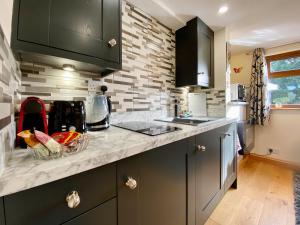 a kitchen with black cabinets and a counter top at Fieldview Snug in Penselwood