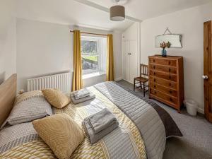 a bedroom with a bed and a dresser and a window at Holme Cottage in Embsay
