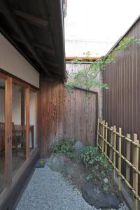 ein Gebäude mit einem Zaun neben einer Holzwand in der Unterkunft Takeya Tenmangu in Kyoto