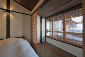 Schlafzimmer mit einem Bett und einem Fenster in der Unterkunft Takeya Tenmangu in Kyoto