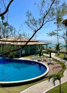 a swimming pool next to a resort with the ocean at O Paraíso é aqui: Pé na Areia em Arembepe in Camaçari