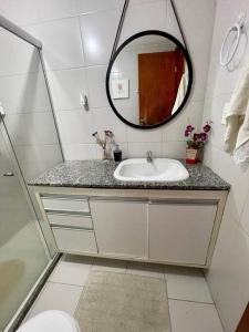 ein Bad mit einem Waschbecken und einem Spiegel in der Unterkunft O Paraíso é aqui: Pé na Areia em Arembepe in Camaçari
