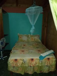 a bed with a comforter and a net at Berkey's Jungle Paradise Resort in Roseau