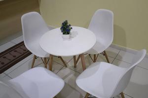 een witte tafel en vier witte stoelen met een plant erop bij Cozy M Suites Android Box, Pool and City Area in Kuala Lumpur