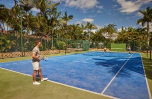 Ein Mann steht auf einem Tennisplatz mit Schläger. in der Unterkunft Brisbane Holiday Village in Brisbane