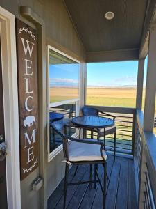 a balcony with two tables and chairs on a porch at Buffalo Jump Guest House in Three Forks