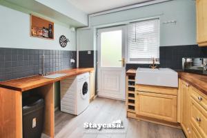 a kitchen with a sink and a washing machine at Quiet Annex With Lovely Garden And Parking in Bredbury