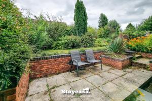un banco sentado en un jardín junto a una pared de ladrillo en Quiet Annex With Lovely Garden And Parking en Bredbury