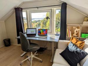 uma secretária com 2 computadores portáteis num quarto com uma janela em Nyoppusset hus med utsikt. em Steinkjer