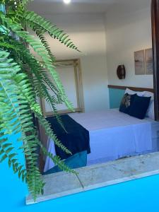 een slaapkamer met een bed en een grote groene plant bij Villa Aconchego Guarajuba in Camaçari