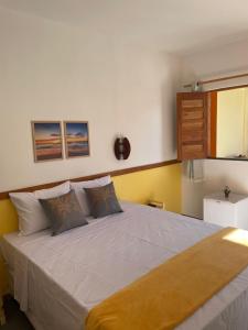 a bedroom with a large white bed with two pillows at Villa Aconchego Guarajuba in Camaçari