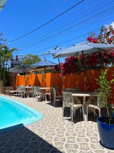 een patio met tafels en parasols naast een zwembad bij Villa Aconchego Guarajuba in Camaçari