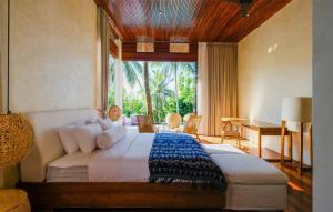 a bedroom with a bed and a desk and a window at EMHILL Estate Lombok in Selong Belanak