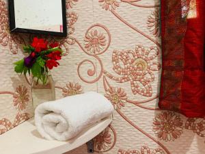 ręcznik na stole z wazonem kwiatów na ścianie w obiekcie Villa Mandala Guest House w mieście Varkala