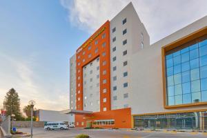 un bâtiment d'hôtel orange et blanc avec un parking dans l'établissement City Express Junior by Marriott Leon Centro de Convenciones, à León