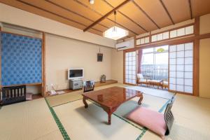 ein Wohnzimmer mit einem Tisch und einem TV in der Unterkunft Hotel Shiiya in Sado