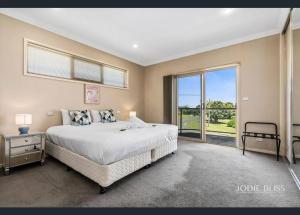 - une chambre avec un grand lit et une grande fenêtre dans l'établissement Freestanding house with ocean view, à Port Campbell