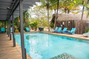 a swimming pool with blue chairs and a hut at Azure Del Mar in Maya Beach