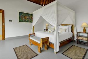 a bedroom with a white bed with a canopy at Suarga Loka Ubud Villa in Ubud
