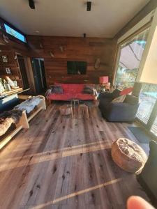 sala de estar con suelo de madera y sofá rojo en Pucón, Espectacular Casa en Pucón