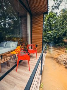 een veranda met 2 rode stoelen en een bed bij TAGUA LODGE in Tena