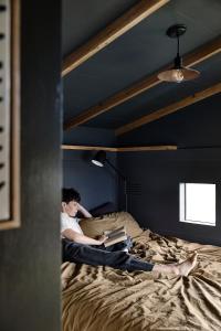 a man sitting on a bed reading a book at A Small, Off-Grid farm house with ocean views. in Illowa