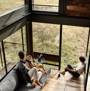 a group of men sitting on a couch looking out the window at A Small, Off-Grid farm house with ocean views. in Illowa