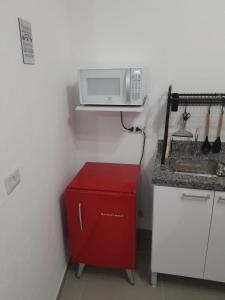 a small kitchen with a microwave and a red cabinet at Studio fantástico in São Paulo