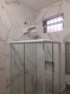 um chuveiro na casa de banho com paredes em mármore branco em Studio fantástico em São Paulo