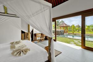 a bedroom with a bed and a view of a pool at Suarga Loka Ubud Villa in Ubud