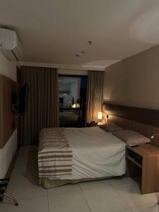 a bedroom with a large bed and a desk at Flat hotel Athos Bulcão. in Brasilia