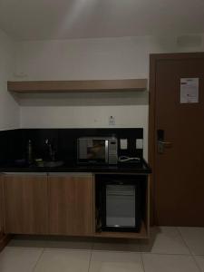 a kitchen with a counter with a microwave and a door at Flat hotel Athos Bulcão. in Brasília