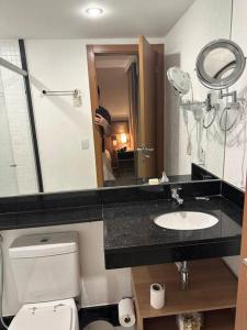 a bathroom with a toilet and a sink and a mirror at Flat hotel Athos Bulcão. in Brasília