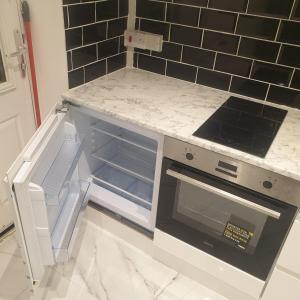 a kitchen with an open oven and black tiles at Bakus Executive Suite in Abbey Wood