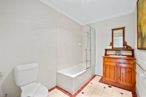 a bathroom with a toilet and a tub and a sink at Charming 3-Bedroom Townhouse with Private Courtyard in Brisbane